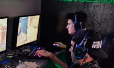 Jogadores em um café de eSports no Brasil usando headsets enquanto competem em jogos online.