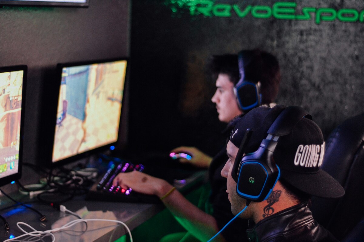 Jogadores em um café de eSports no Brasil usando headsets enquanto competem em jogos online.