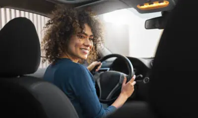 Mulher sorrindo enquanto dirige um carro