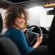 Mulher sorrindo enquanto dirige um carro
