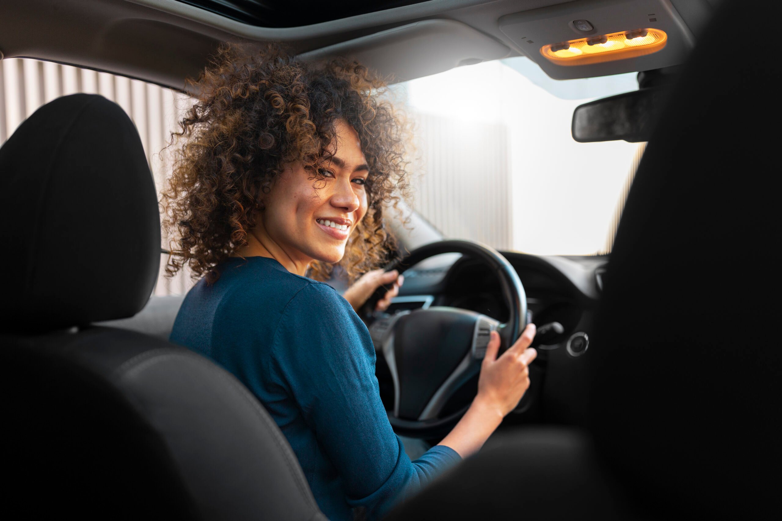 Mulher sorrindo enquanto dirige um carro