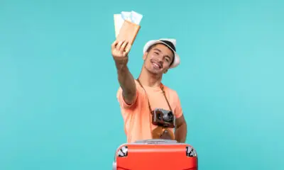 Homem com mala de viagem segurando passagens